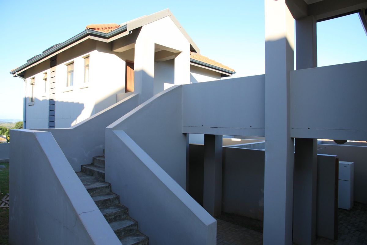 Exterior view of the apartment building featuring a concrete staircase, structural pillars, and a tiled roof.