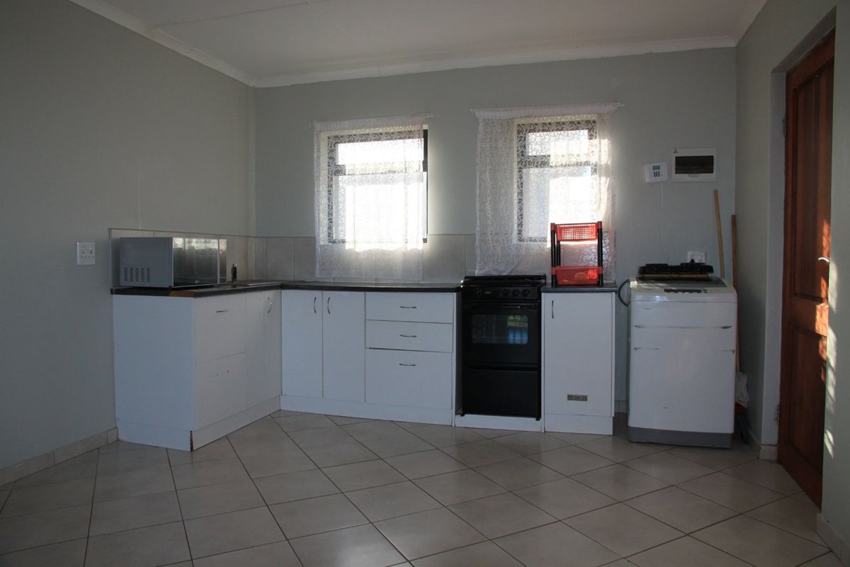 Functional kitchen featuring white cabinetry, tiled flooring, a tiled backsplash, and a dedicated space for laundry appliances.