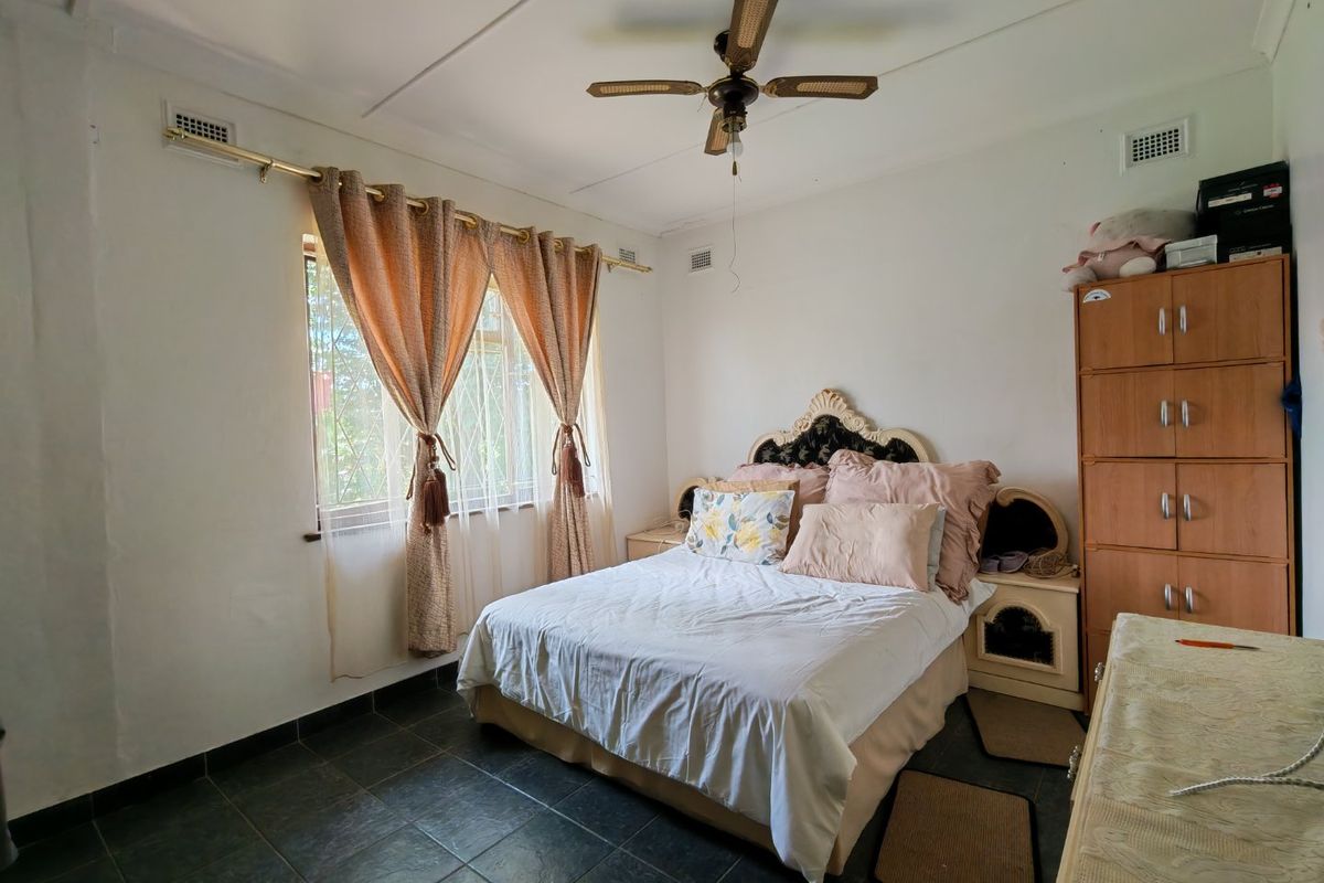 A functional bedroom featuring dark tiled flooring, a ceiling fan, and built-in storage cabinetry, offering a neutral base for potential updates.