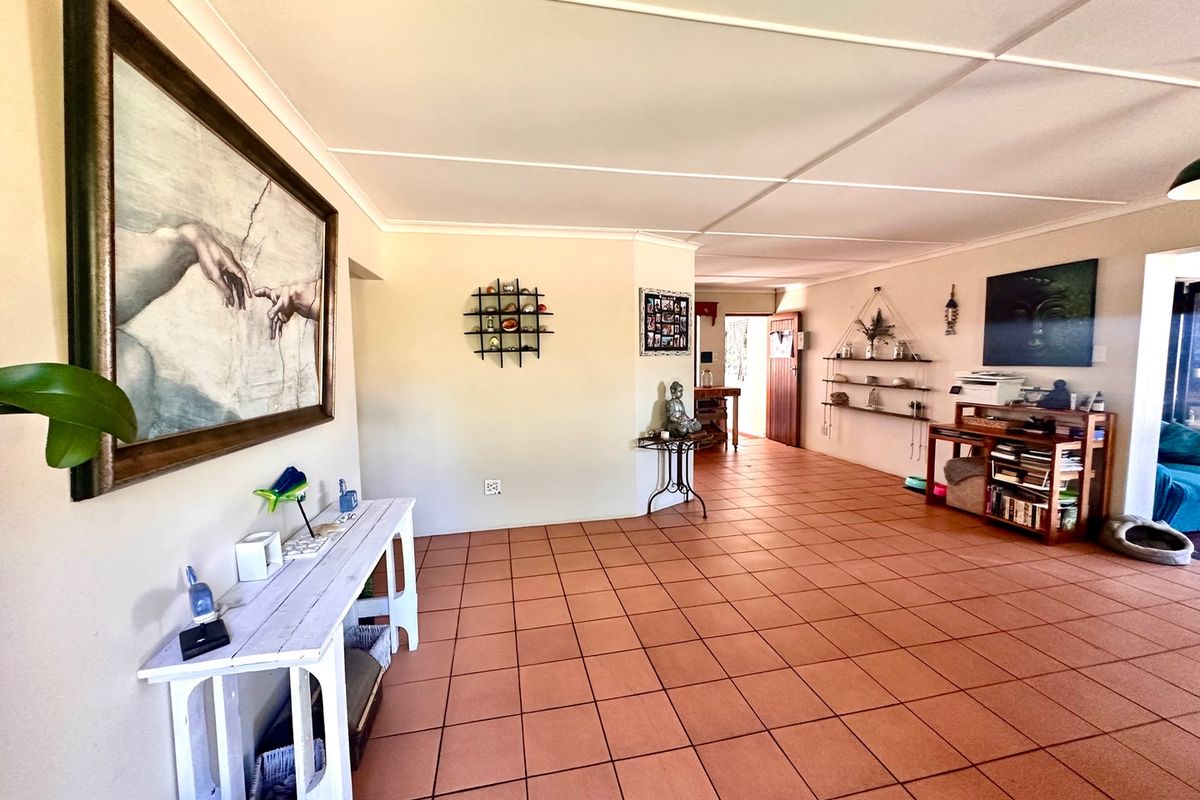 Spacious living area featuring terracotta floor tiles and neutral wall finishes, providing a versatile open-plan layout with access to adjacent rooms.