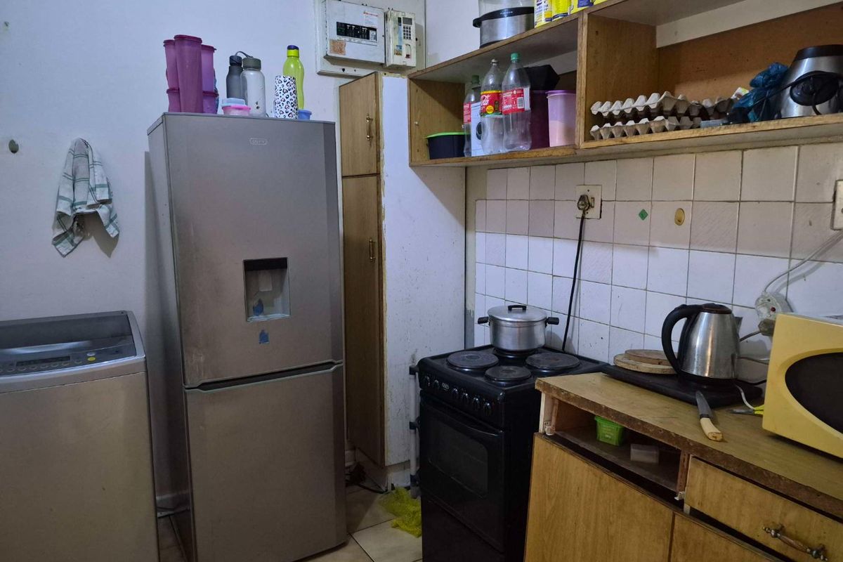 Compact kitchen featuring tiled splashbacks, built-in shelving, and a freestanding stove, offering a functional layout with potential for modernization.