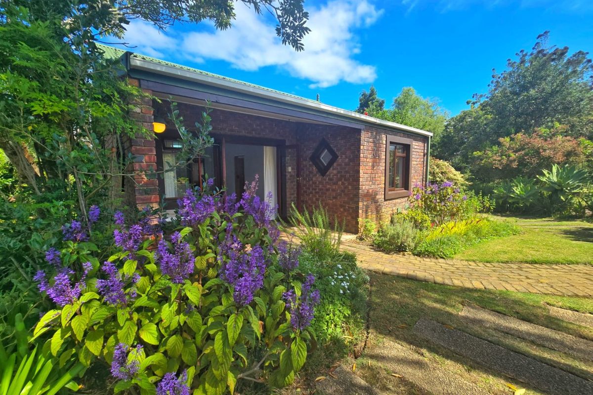 A charming face brick townhouse exterior featuring a paved garden path, lush landscaping, and direct access through double doors to the rear garden.