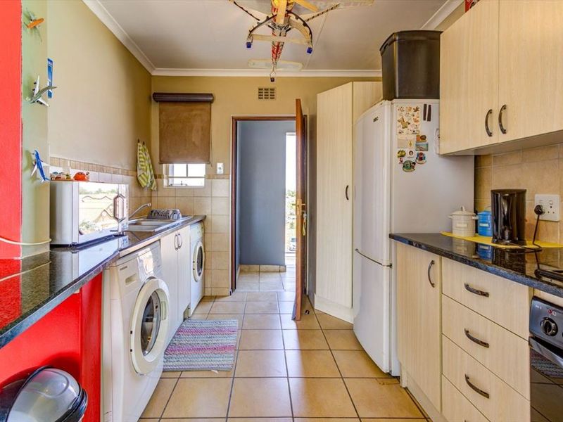 Functional kitchen featuring laminate cabinetry, granite countertops, tiled backsplash, and integrated laundry plumbing, providing a practical workspace with direct access to the exterior.