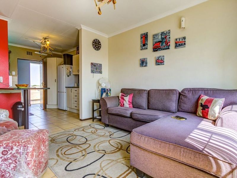Open-plan living area featuring tiled floors, a breakfast bar, and an adjoining kitchen space with built-in cabinetry.
