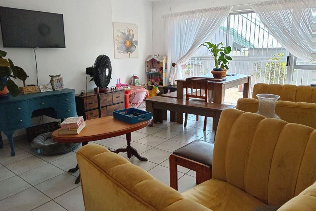 Open-plan living and dining area featuring tiled flooring and large sliding glass doors with security gate access to the exterior.
