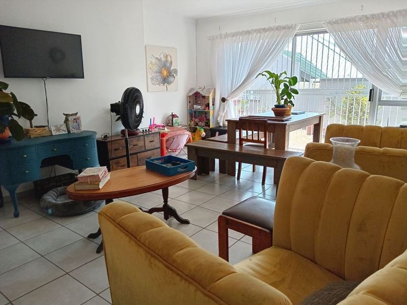 Open-plan living and dining area featuring tiled flooring and large sliding glass doors with security gate access to the exterior.