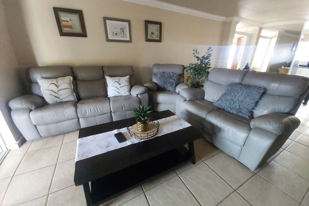 A comfortable living room area featuring neutral tiled flooring and classic cove cornicing, providing a functional and well-maintained space for relaxation.