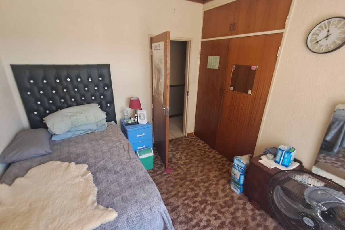 A bedroom featuring built-in wooden wardrobes and carpeted flooring, offering a functional space with potential for modernization.