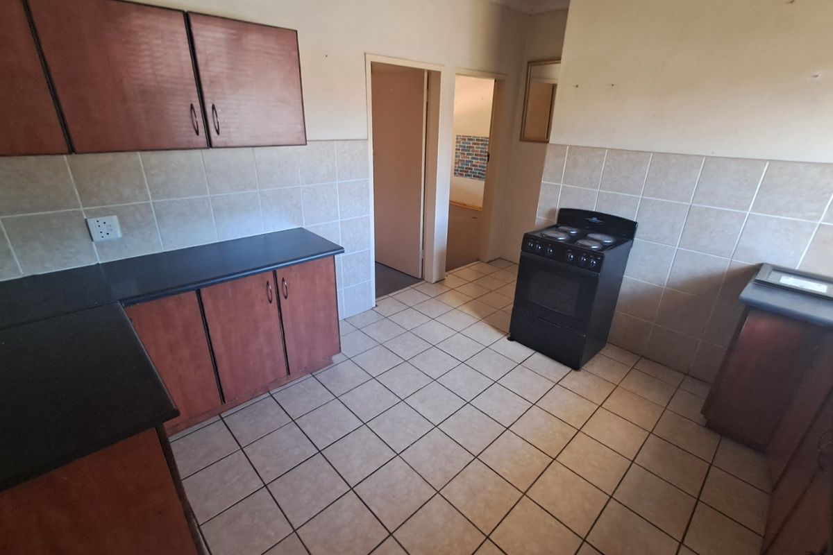 A functional kitchen featuring laminate cabinetry, tiled splashbacks, and a freestanding electric stove, offering a blank canvas for potential modern updates.