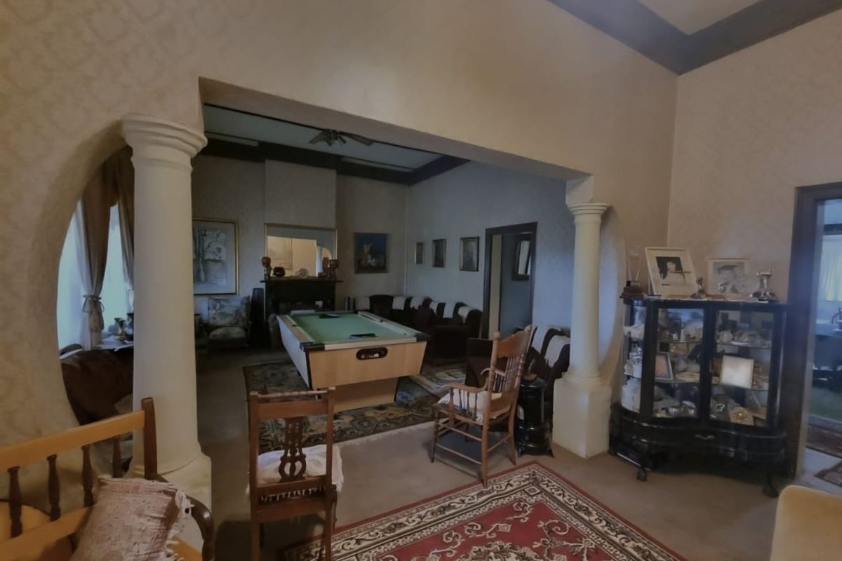 Spacious living area featuring decorative columns, a fireplace, and high ceilings, offering a traditional layout with connected living spaces.