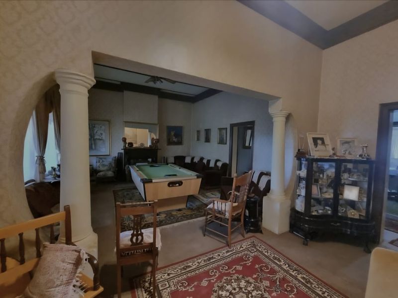 Spacious living area featuring decorative columns, a fireplace, and high ceilings, offering a traditional layout with connected living spaces.