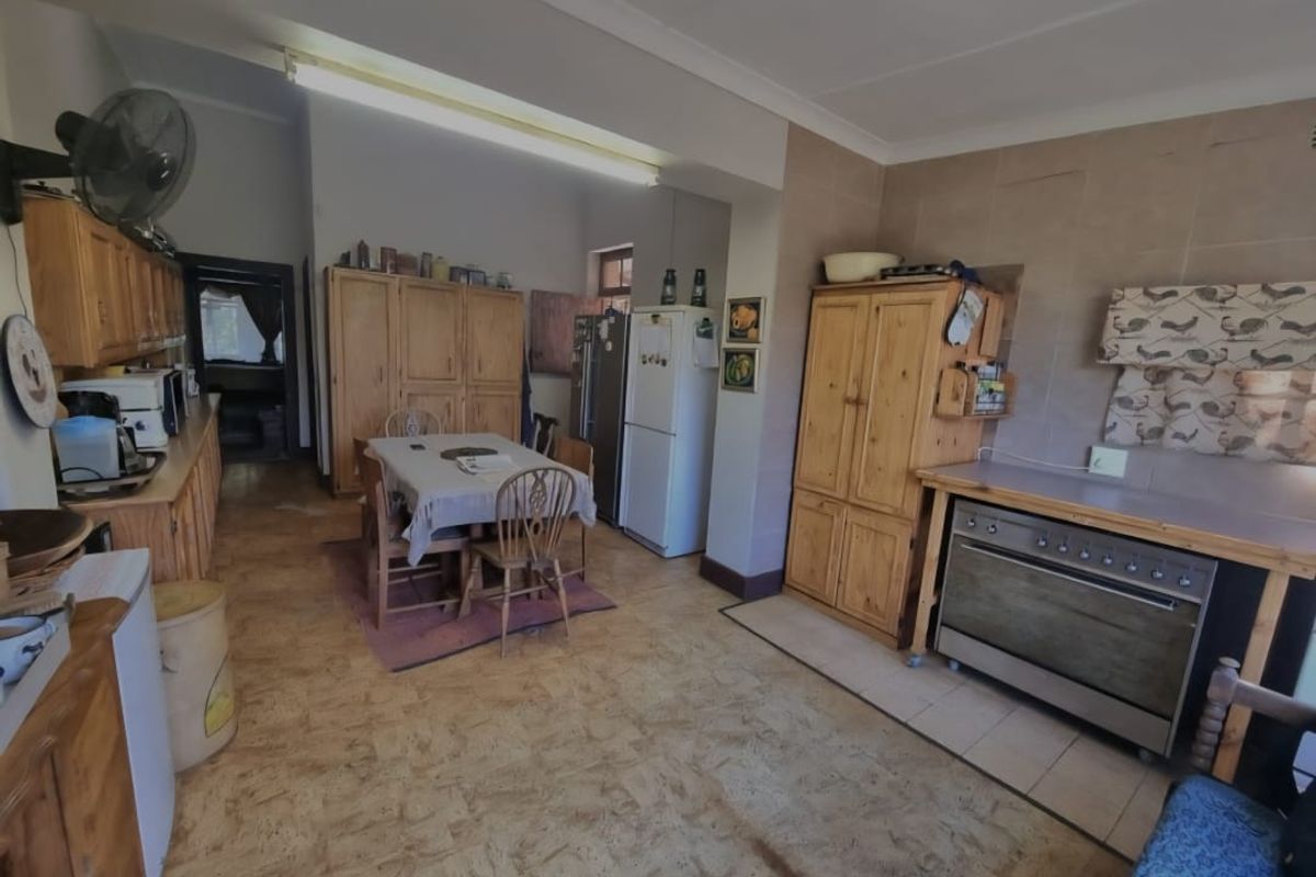 Spacious farm-style kitchen featuring extensive wooden cabinetry, a freestanding oven, and tiled splashbacks, offering a functional layout with potential for modern updates.