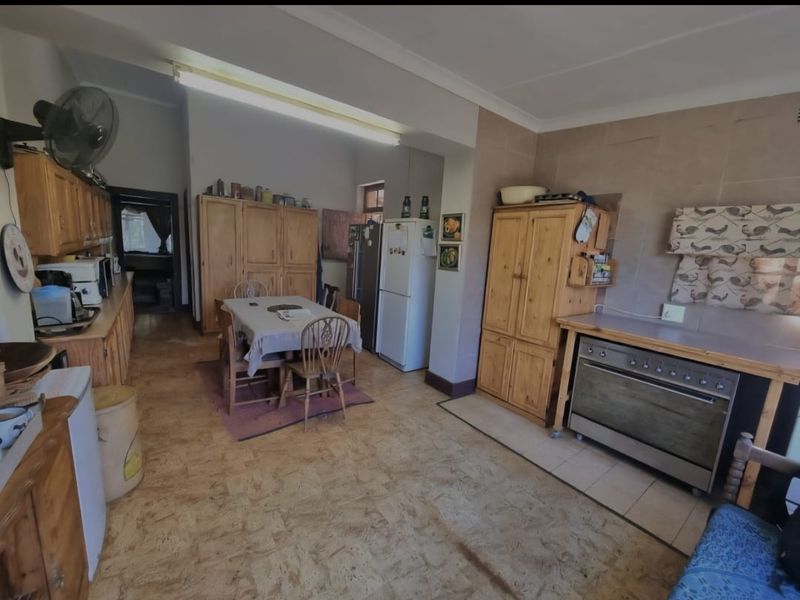 Spacious farm-style kitchen featuring extensive wooden cabinetry, a freestanding oven, and tiled splashbacks, offering a functional layout with potential for modern updates.