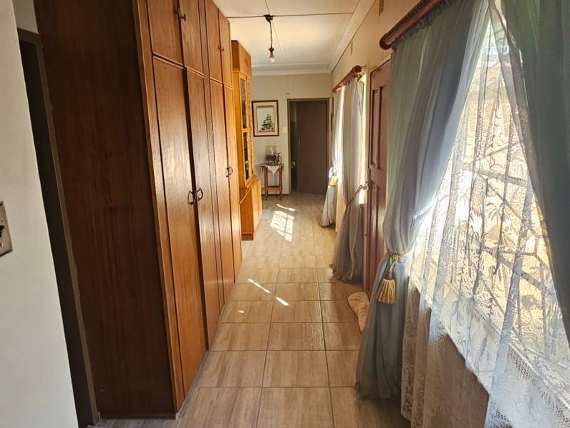 A functional hallway featuring extensive built-in wooden cabinetry for storage and durable tiled flooring, providing a clean and practical transition space.