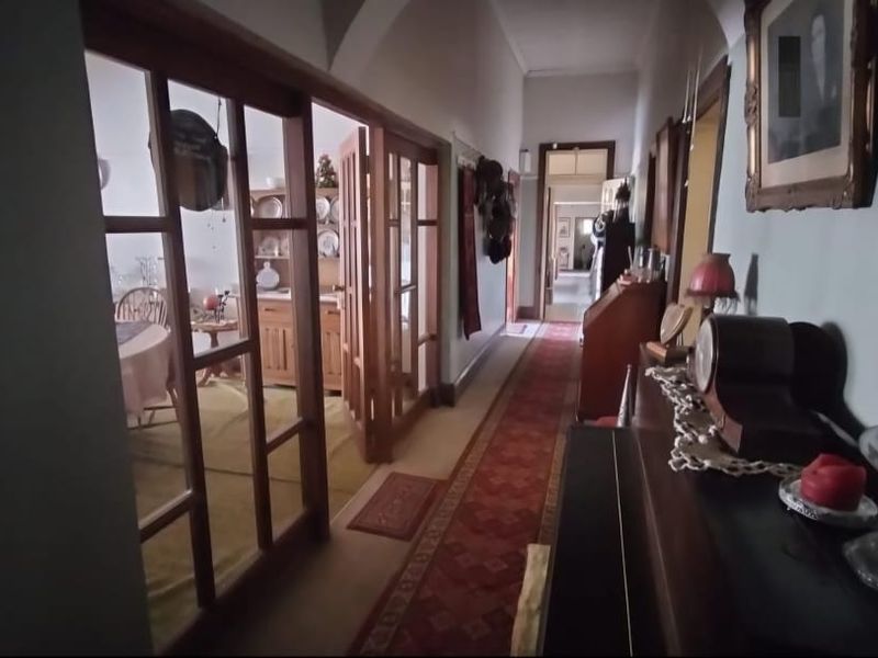 A long interior hallway featuring timber-framed glass doors leading into adjacent living spaces, characterized by traditional architectural details and an arched ceiling.