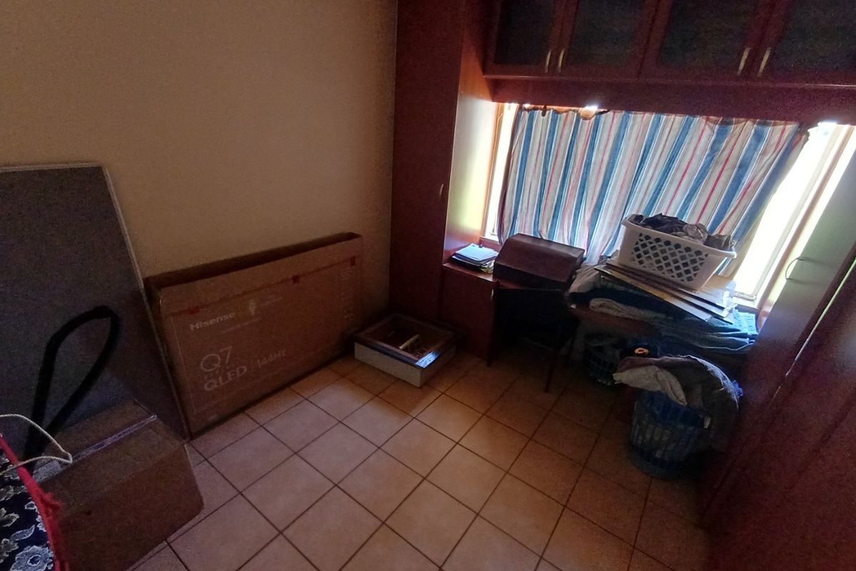 A bedroom space featuring built-in cabinetry and tiled flooring, currently used for storage.