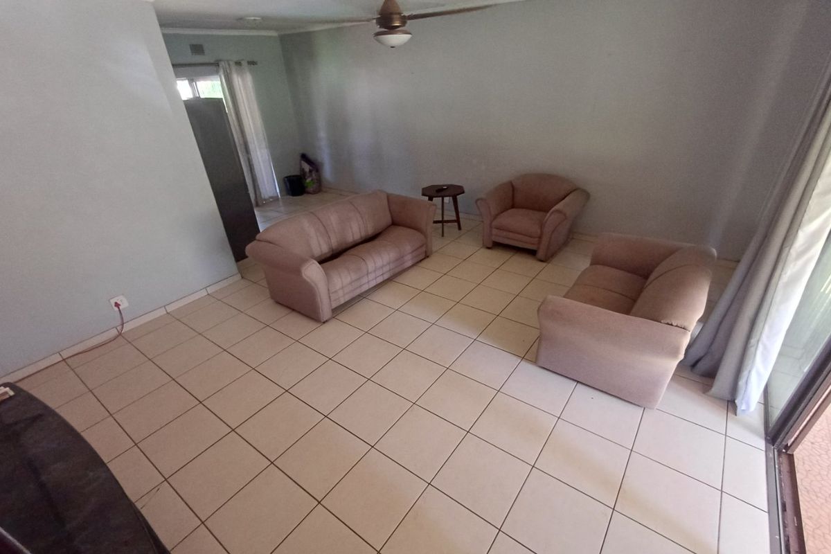 Spacious living room featuring ceramic floor tiles, a ceiling fan, and sliding glass door access to the exterior.