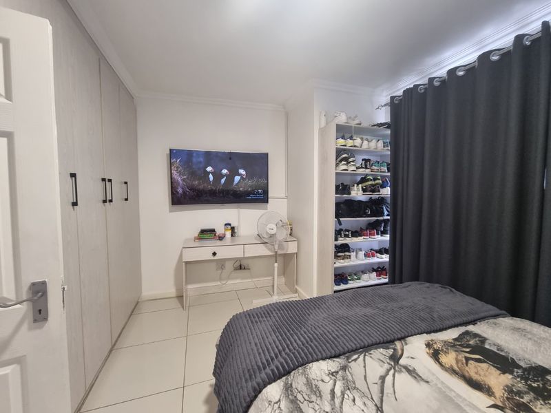 A well-maintained bedroom featuring neutral tiled flooring, built-in cupboards, and coving detail, providing a functional and clean living space.