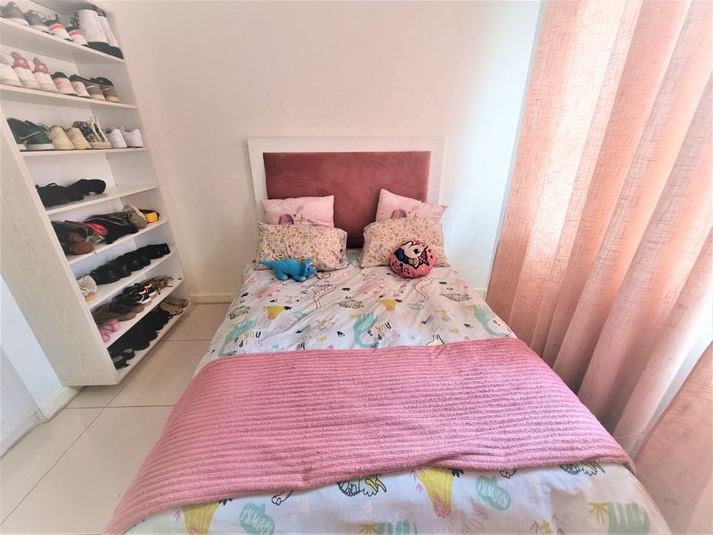 A well-maintained bedroom featuring tiled flooring and a built-in shelving unit for storage.