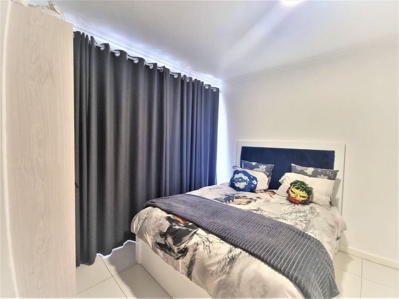 A well-maintained bedroom featuring tiled flooring, coved ceilings, and full-length curtain tracks, providing a clean and functional living space.