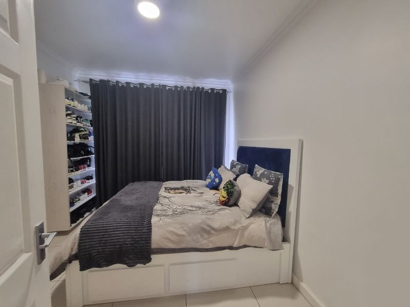 A well-maintained bedroom featuring tiled flooring, built-in shelving, and decorative cove cornicing, providing a clean and functional living space.