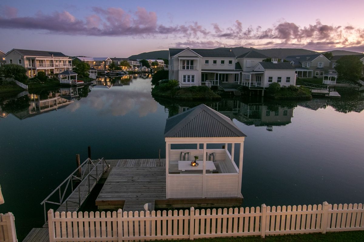 Aerial view of a waterfront property featuring a private jetty with a gazebo, overlooking a serene canal in a residential estate.