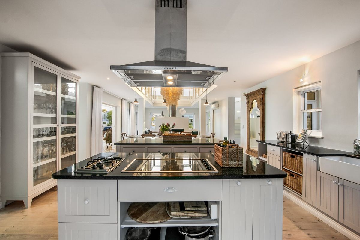 A spacious, high-end kitchen featuring a large central island with integrated gas and induction hobs, granite countertops, and custom cabinetry.