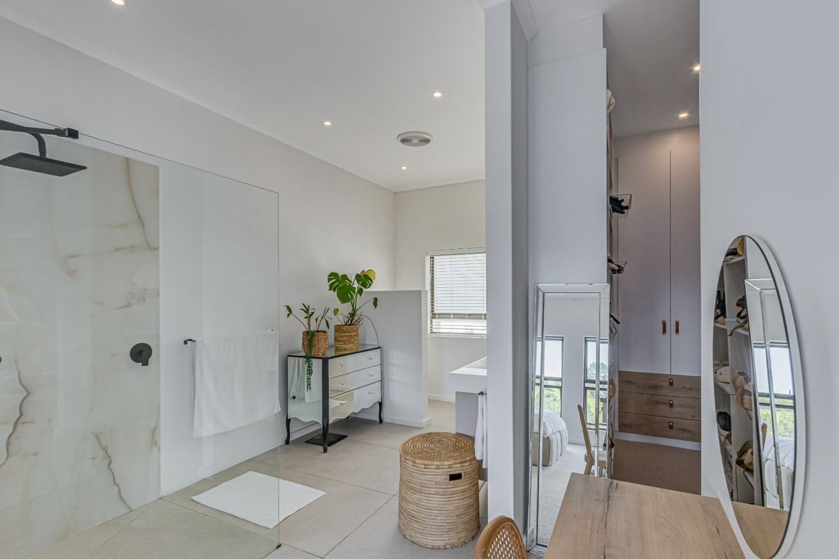Modern bathroom featuring a spacious walk-in shower with marble-look wall cladding, black fixtures, and integrated storage cabinetry.