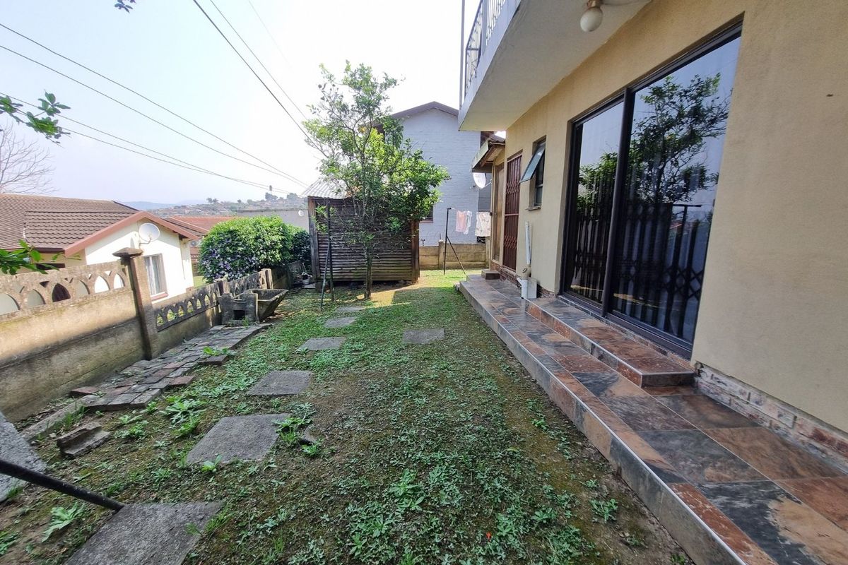 Rear exterior view featuring a tiled patio, sliding glass doors, and a garden area with boundary walling.