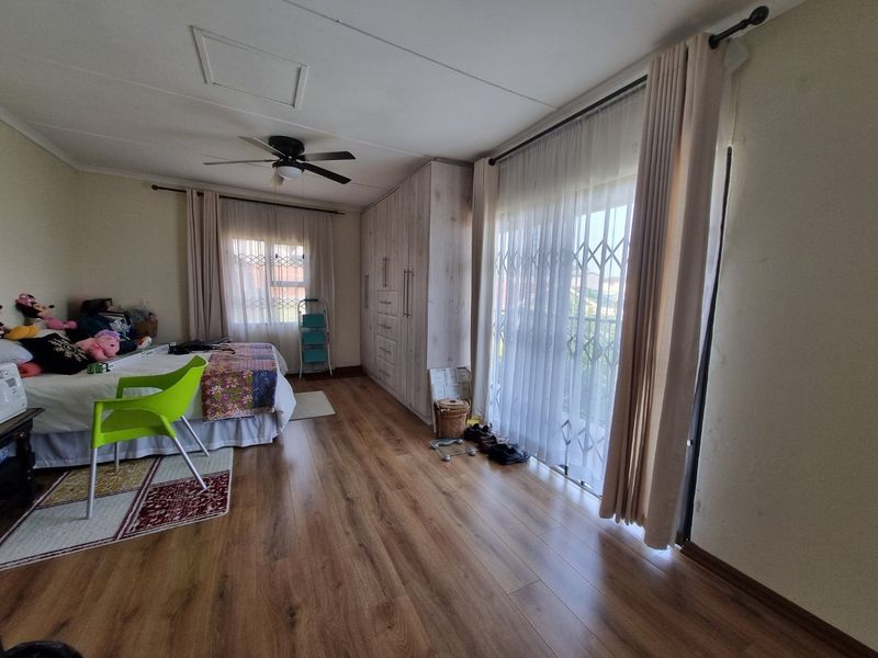 Spacious bedroom featuring laminate flooring, built-in cupboards, a ceiling fan, and a sliding door providing access to an outdoor area.