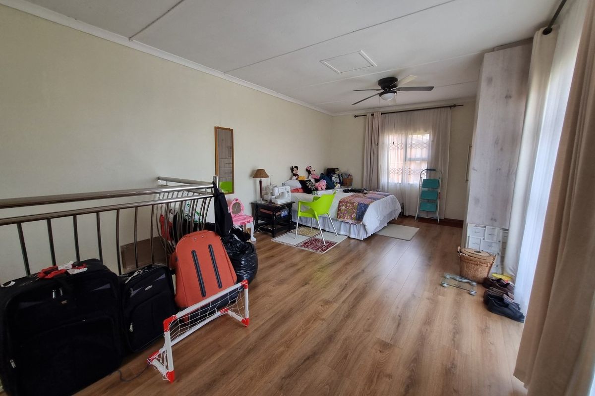 Spacious bedroom featuring laminate flooring, a ceiling fan, and a metal balustrade overlooking a lower level.