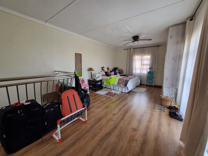Spacious bedroom featuring laminate flooring, a ceiling fan, and a metal balustrade overlooking a lower level.