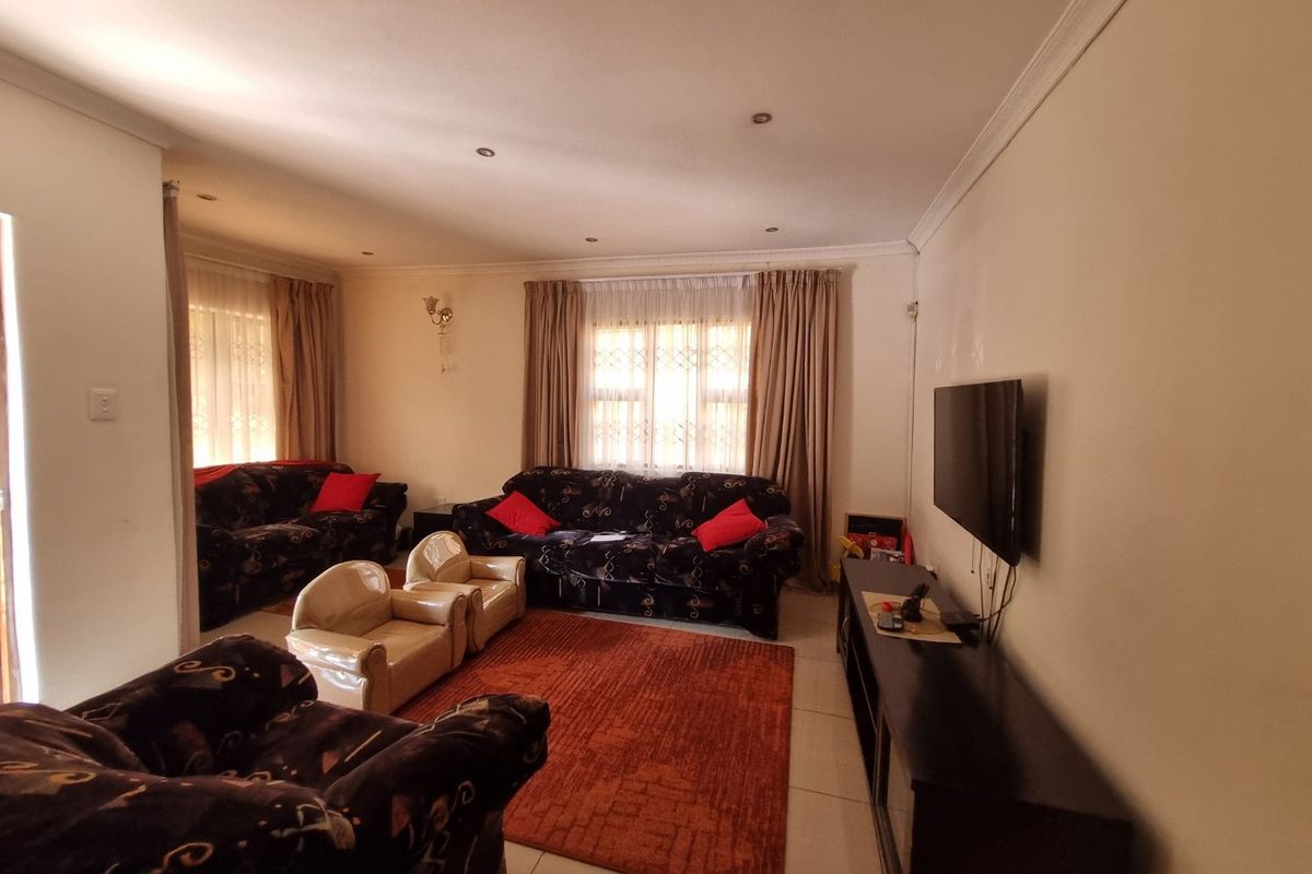 A spacious living room featuring tiled flooring, recessed downlighting, and decorative ceiling cornicing, providing a comfortable and functional family area.