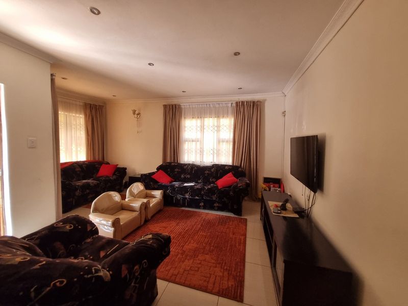 A spacious living room featuring tiled flooring, recessed downlighting, and decorative ceiling cornicing, providing a comfortable and functional family area.