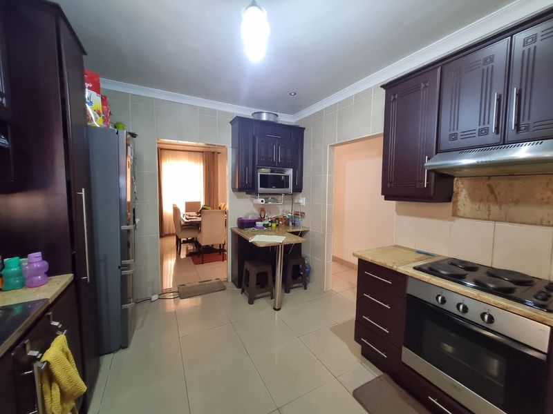 Functional kitchen featuring dark wood cabinetry, granite countertops, built-in oven, and hob, with tiled flooring and backsplash throughout.
