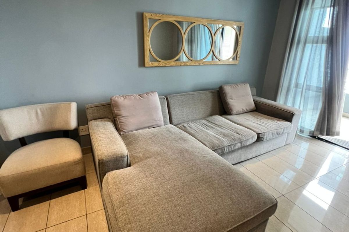 A well-lit living room featuring neutral tiled flooring, a feature wall, and large sliding glass doors providing natural light.
