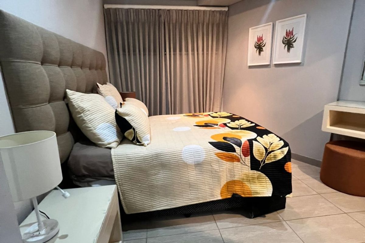 A well-maintained bedroom featuring neutral wall tones, modern tiled flooring, and recessed ceiling lighting, creating a clean and comfortable living space.