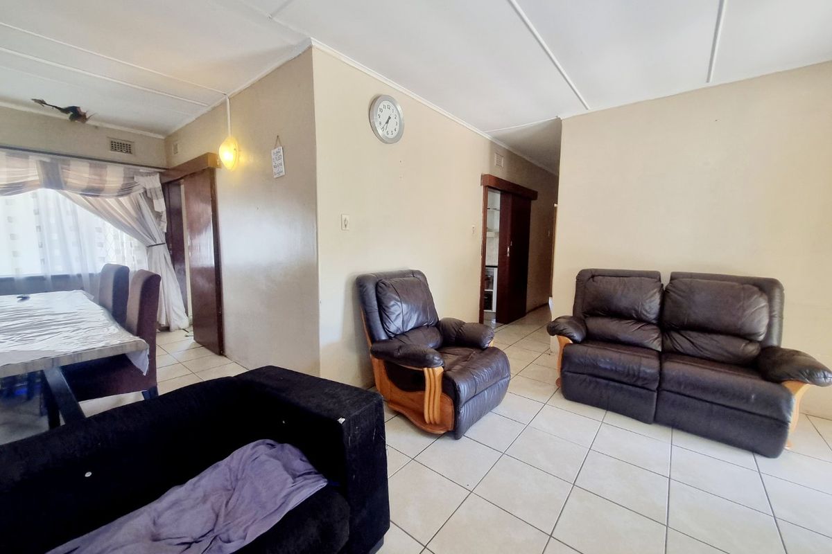 A living room area featuring ceramic floor tiles and sliding door access, showing signs of wear on the ceiling and walls.