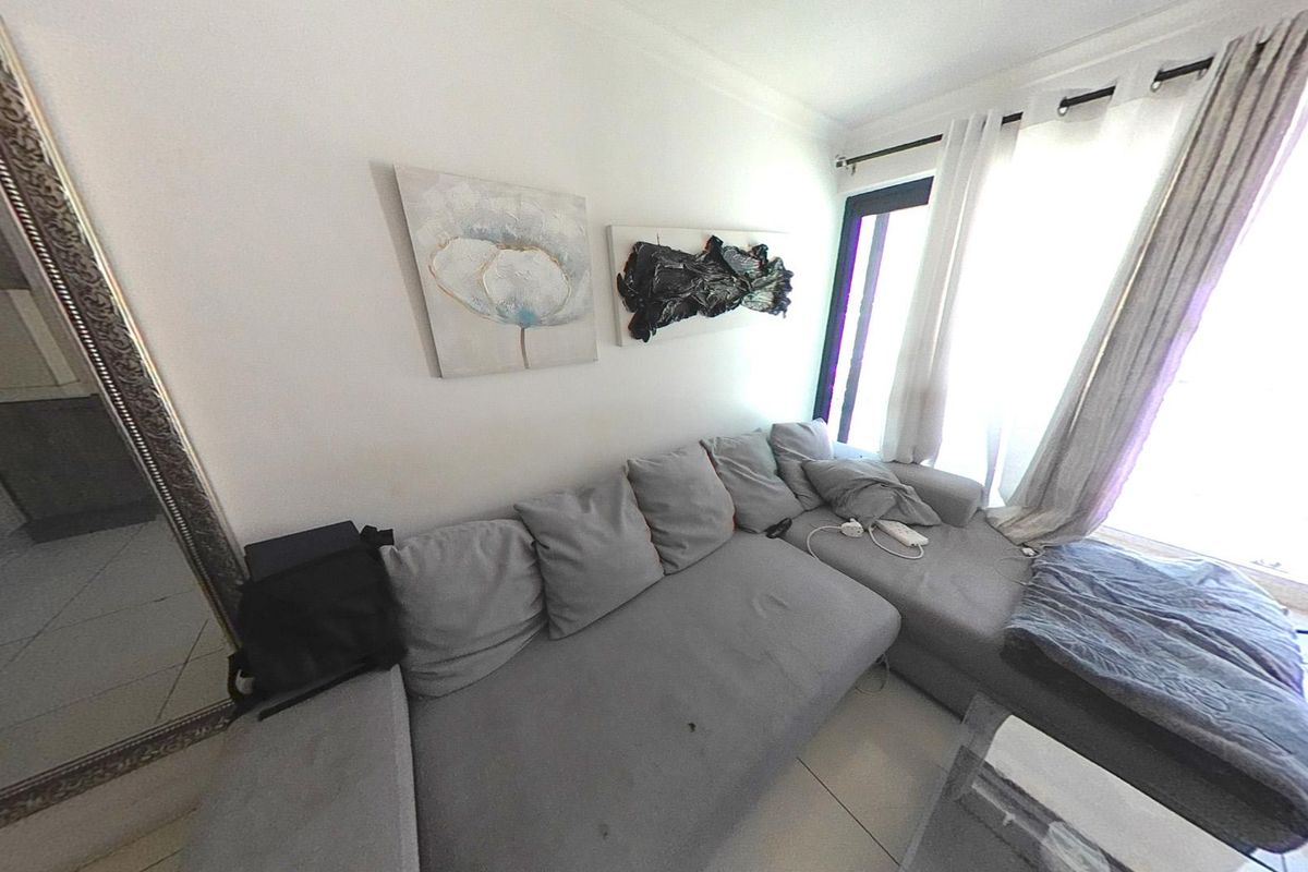 A living room area featuring tiled flooring and a large sliding glass door providing natural light access.