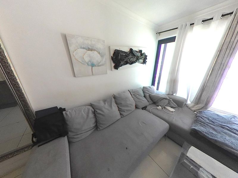 A living room area featuring tiled flooring and a large sliding glass door providing natural light access.