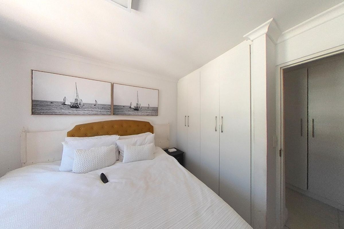 A well-maintained bedroom featuring built-in cupboards, crown molding, and neutral finishes, providing a clean and functional living space.