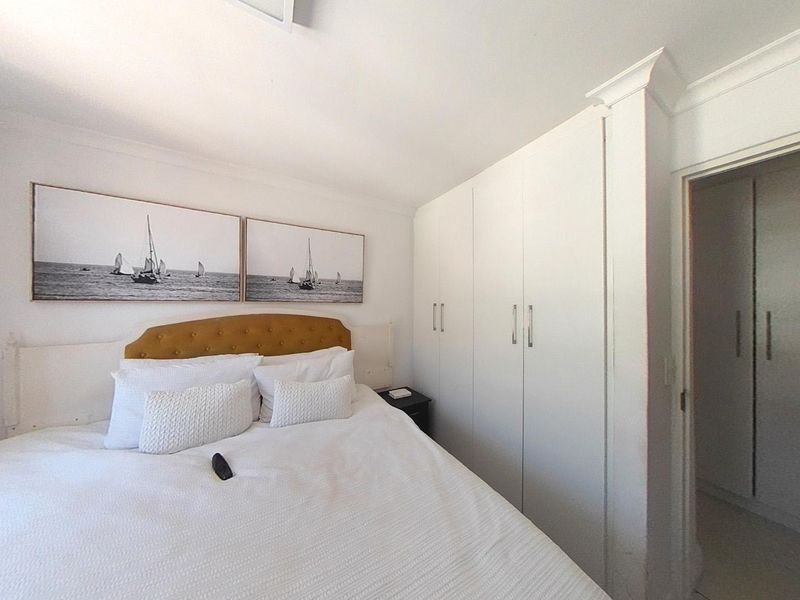 A well-maintained bedroom featuring built-in cupboards, crown molding, and neutral finishes, providing a clean and functional living space.