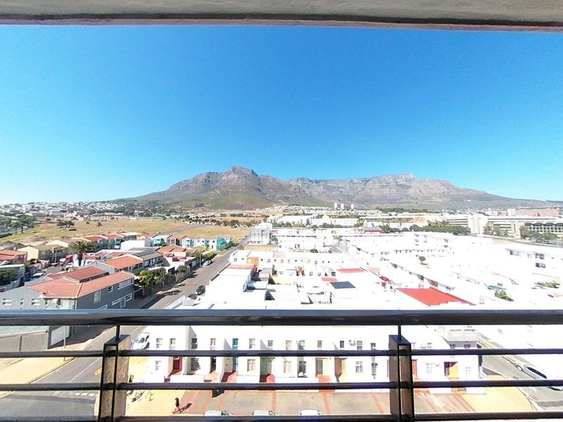 Elevated panoramic view of the surrounding neighborhood and mountain range, captured from a balcony with a metal safety railing.