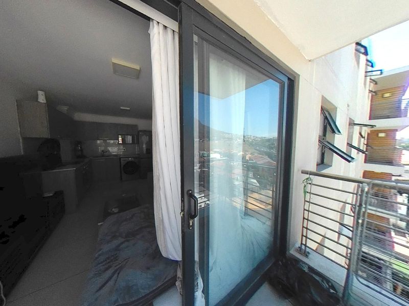A balcony area featuring a metal balustrade and a sliding glass door providing access to the interior living space.