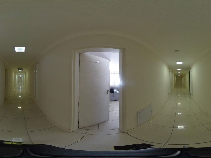 A wide, well-lit apartment hallway featuring tiled flooring and recessed ceiling lights, providing access to multiple internal rooms.