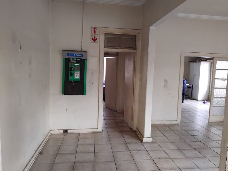 A vacant hallway featuring tiled flooring and an archway, showing signs of wear and requiring cosmetic updates to the walls and finishes.