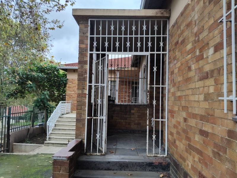 A covered entrance patio featuring brick construction and a security gate, providing access to the home's exterior.