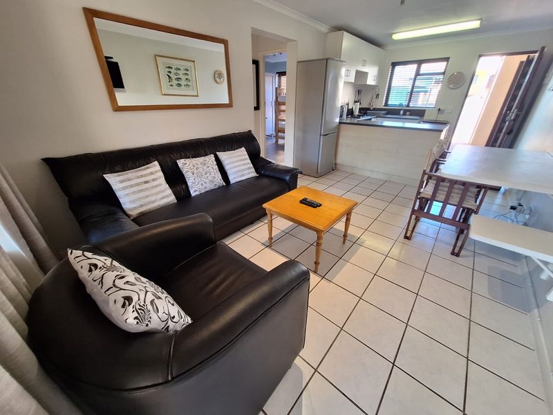 Open plan living and dining area featuring tiled flooring and a functional kitchen with built-in cabinetry and countertop space.