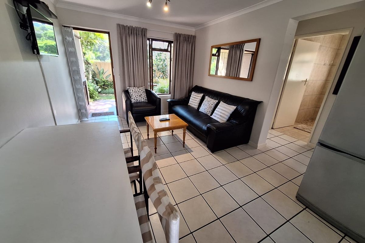 Open-plan living area featuring tiled flooring, neutral walls, and direct access to an outdoor patio space through a sliding door.