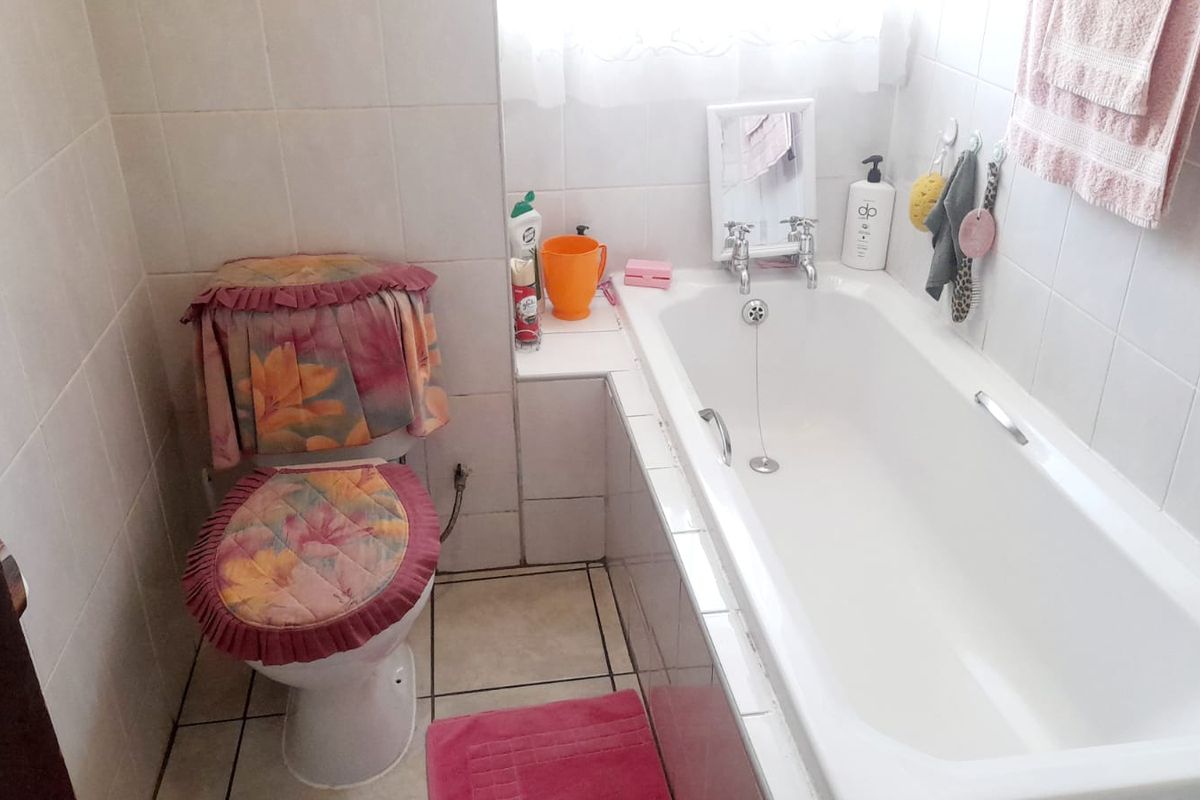 A functional bathroom featuring a standard bathtub and toilet with tiled wall and floor finishes.